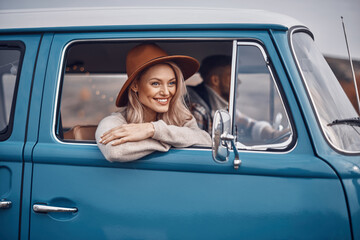 Beautiful young woman looking through a window and smiling while her boyfriend driving a car