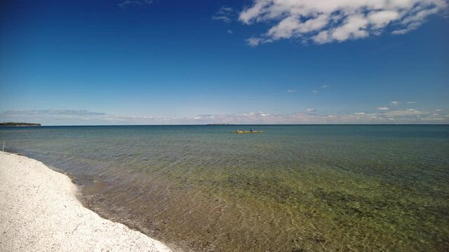 Hiking the shoreline of Lake Ontario. Two kayakers paddle on a beautiful fall day.
