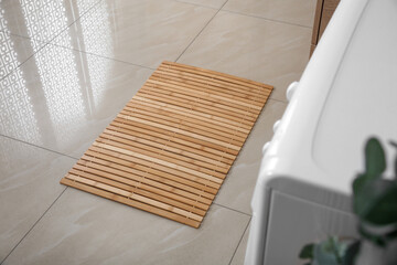 Wooden mat on floor near washing machine in bathroom