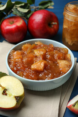 Tasty apple jam in bowl and fresh fruits on blue table