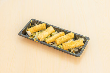 Portion of takeaway with crispy fried Vietnamese spring rolls on wooden table