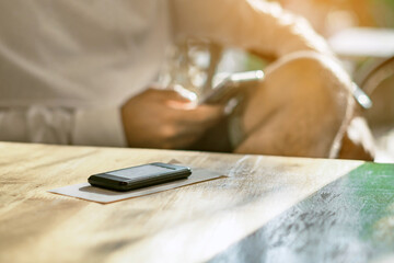 Wireless Calling System Restaurant or Pager Customers System with invoice on table with blur image of man using cellphone in background.Alarm signal when food is done.Queue wireless pager for calling.