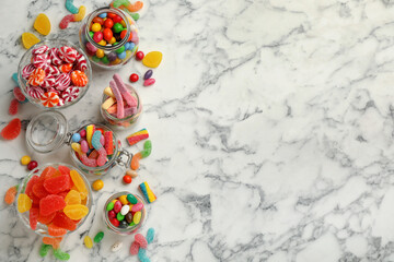 Jars with different delicious candies on white marble table, flat lay. Space for text