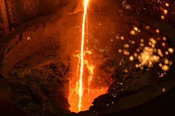 Molten iron flow. Liquid metal is poured into the ladle in a thin stream