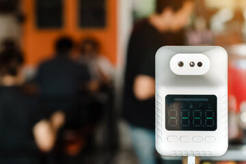 Digital automatic body measuring temperature machine for measuring body temperature by placing a hand over the sensor in a coffee shop for mandatory checks of customers during the Covid-19 pandemic.