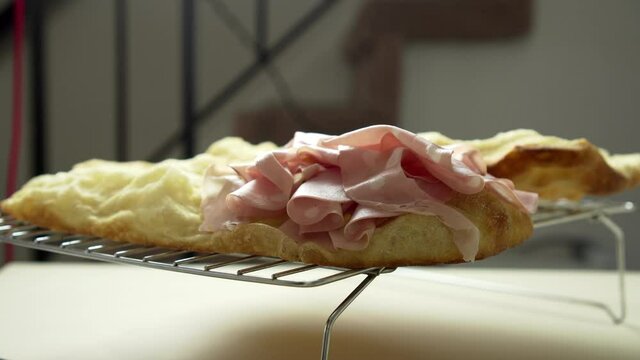 Time Lapse: The Chef is placing delicious Italian Mortadella on top of a crusty and airy pizza sandwich.