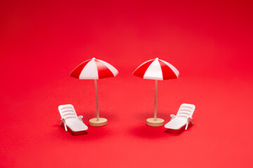 Two sun loungers and red umbrellas on a red background.
