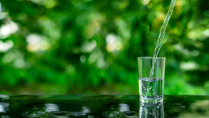 Water flows into a glass placed on a wooden bar.
