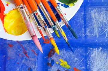 Top view of painters brushes on plastic palette with colorful watercolour. Copy space