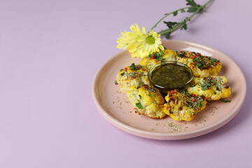 Concept of tasty food with baked cauliflower on violet background