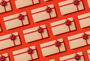 Seamless pattern of holiday gift boxes wrapped in craft paper with a red bow on red background. Top...