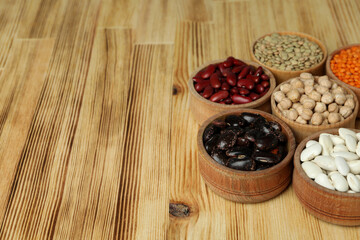 Obraz na płótnie Canvas Bowls with different types of beans on a wooden background