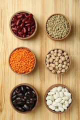 Flat lay composition with different types of beans on a wooden background