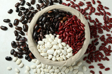 Basket with different types of beans on white textured background