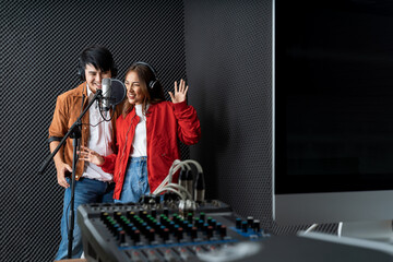 Asian couple singers in a recording studio using a studio microphone with passion in music recording studio