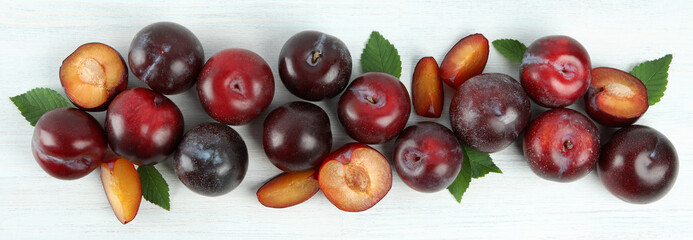 Flat lay composition with plums on white wooden background