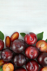 Flat lay composition with plums on white wooden background