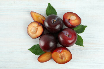 Flat lay composition with plums on white wooden background