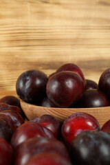 Plums in a wooden bowl on a wooden table