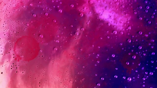 Bubbles moving upwards in pink and blue paint.