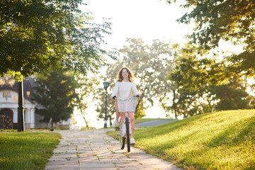 Obraz premium A young girl riding a bike in sunlight in the park