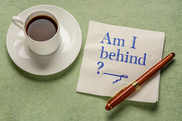 Am I my behind? A question written on napkin with a cup of coffee. Deadline, delay and stress concept.