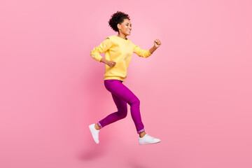 Fototapeta na wymiar Photo of beautiful attractive lady wear yellow pullover running fast jumping high smiling isolated pink color background