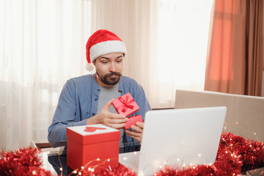 Hipster Man With Red Cup Sitting Home At Christmas Time. Virtual Christmas Thanksgiving House Party. Online Team Meeting Video Conference Calling From Home.