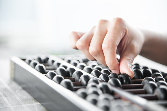 Close of hand using abacus with bright backdrop