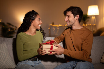 Husband Giving Gift Box To Wife On Christmas At Home