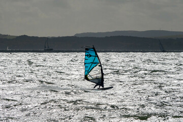 Naklejka premium Wind surfer out on The Solent Hampshire England with the Isle of Wight in the background on a grey Autumn day