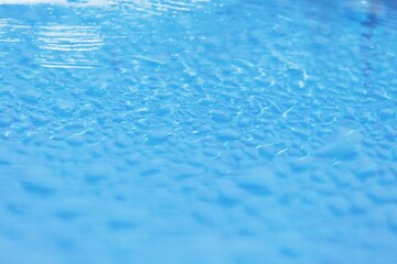 Transparent blue colored clear water surface texture with ripples and splashes and bubbles.