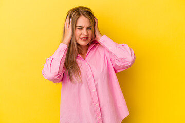 Young russian woman isolated on yellow background covering ears with hands.