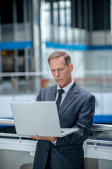Fototapeta premium Serious man looking at laptop at airport