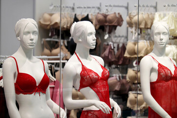 Fototapeta na wymiar Female mannequins in red underwear on background of racks with bra and panties in window of lingerie store