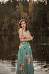 Autumn portrait of a girl standing in a forest lake. The girl in the lake against the background of the forest.