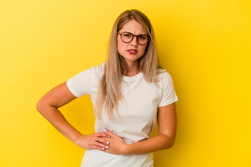 Young russian woman isolated on yellow background having a liver pain, stomach ache.