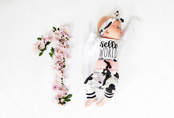 1-month-old baby girl with pink flowers. Baby milestone one month. One month old newborn baby. Kids...