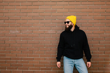 City portrait of handsome hipster guy wearing black blank hoodie with space for your logo or design. Mockup for print. Hoodie template