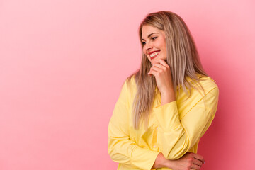 Young russian woman isolated on pink background relaxed thinking about something looking at a copy space.