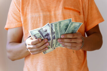 Man counts the money. concept: investments and loans. a man in a orange T-shirt holds paper dollars...