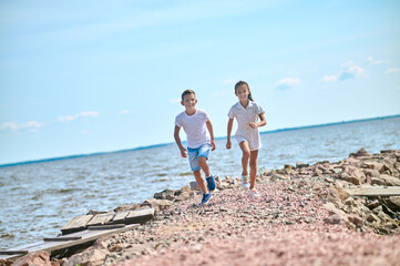 Fototapeta premium Two kinds running on a beach and feeling great