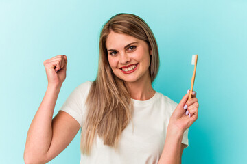 Young russian woman holding a toothbrush isolated on blue background