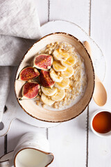 Close up of bowl with oatmeal porridge with figs and bananas for breakfast