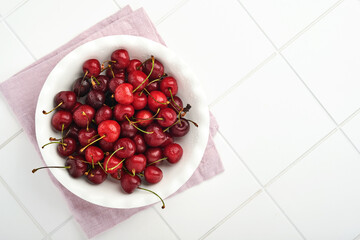 Cherry with water drops on heart shaped plate on white stone table. Fresh ripe cherries. Sweet red cherries. Top view. Rustic style. Fruit Background