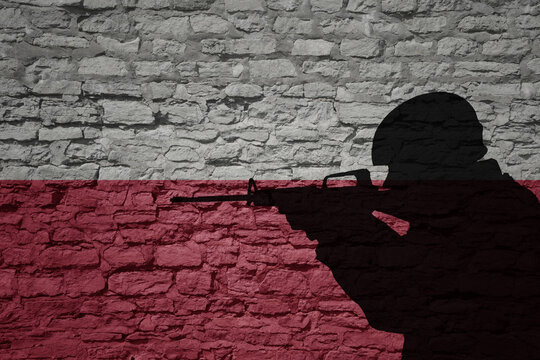 Soldier silhouette on the old brick wall with flag of poland country.