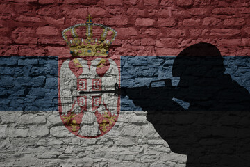 Soldier silhouette on the old brick wall with flag of serbia country.