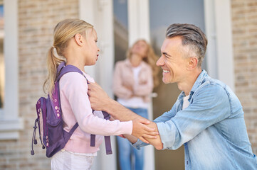 Fototapeta premium Smiling man crouching near his little daughter