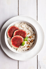 Top view of bowl with oatmeal porridge decorated with figs and nuts