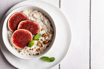 Top view of bowl with oatmeal porridge decorated with figs and nuts